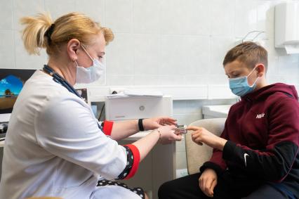 Санкт-Петербург. Врач проводит осмотр пациента перед вакцинацией от коронавирусной инфекции COVID-19 вакциной `Спутник М` в детской поликлинике #10.