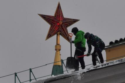 Москва. Сотрудники коммунальной службы чистят крышу здания Арсенала Московского Кремля от снега.