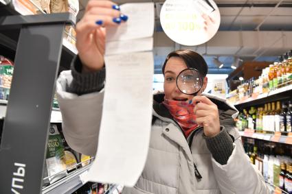 Москва. Девушка изучает чек в продуктовом магазине.