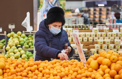 Пермь. Женщина выбирает мандарины в магазине.