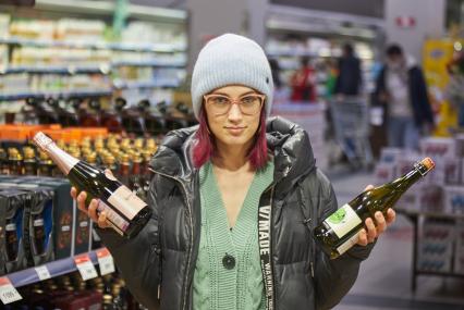Пермь. Девушка выбирает вино в магазине.