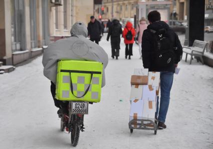 Москва.   Сотрудники службы доставки на улице города.