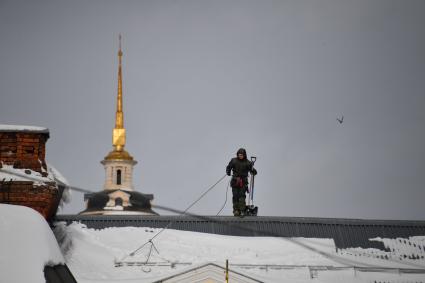 Суздаль.  Мужчина чистит снег на крыше.