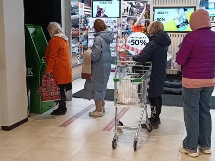 Москва.  Люди стоят в очереди к банкомату  в торговом центре.