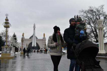 Москва. 8 марта. Девушка с букетом тюльпанов гуляет с семьей на ВДНХ.