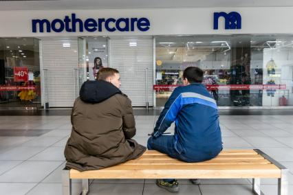 Челябинск. Молодые люди сидят у закрытого магазина Mothercare в торговом центре. Магазины Mothercare приостановили продажи в России из-за военной спецоперации РФ на Украине.