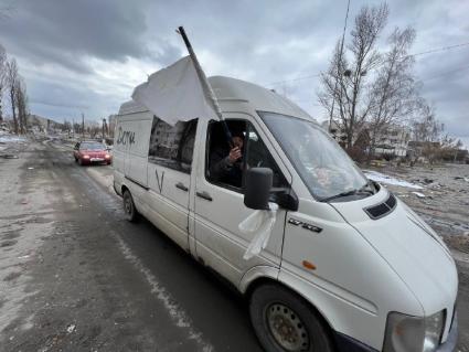 Киевская область. п.Бородянка. Пригород Киева. Военная операции РФ по демилитаризации Украины. Украинские беженцы в белом микроавтобусе с надписью `Дети` и белым флагом в окне едут по дороге.