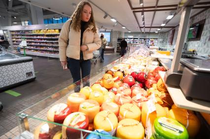 Санкт-Петербург. Девушка выбирает сыр в продуктовом магазине.