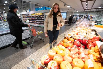 Санкт-Петербург. Девушка выбирает сыр в продуктовом магазине.