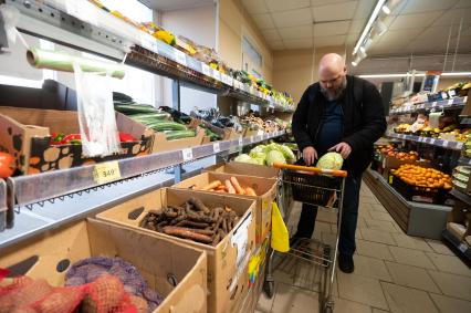 Санкт-Петербург. Мужчина выбирает капусту в продуктовом магазине.