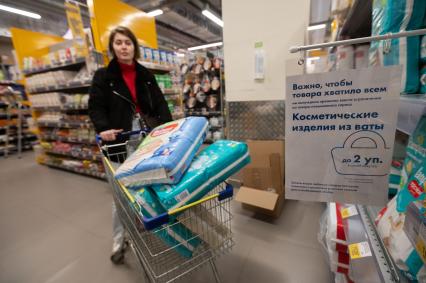 Санкт-Петербург. Девушка везет в тележке упаковки с детскими подгузниками в магазине.