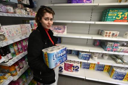 Санкт-Петербург. Девушка держит в руках упаковку с туалетной бумагой в магазине.