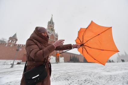 Москва. Девушка с зонтом во время сильного ветра на Красной площади.