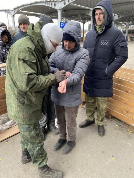 Украина. г.Мариуполь. Местные жители стоят в очереди в гипермаркет Metro за гуманитарной помощью, организованной партией `Единая Россия`. На входе в гипермаркет горожанам ставят номера на ладони – чтобы был порядок.