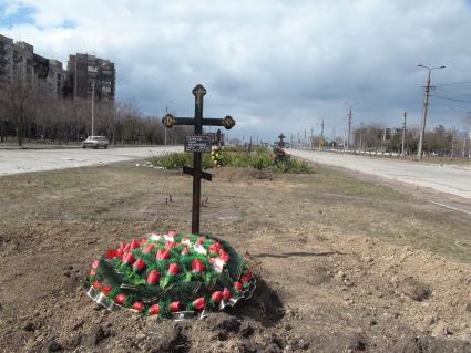 Украина. г.Мариуполь. Местные жители хоронят своих близких в городе. Могилы у дороги.