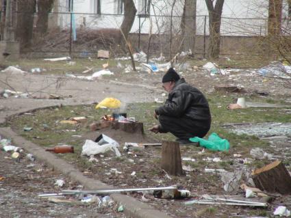 Украина. г.Мариуполь. Местный житель готовит обед на костре во дворе дома.