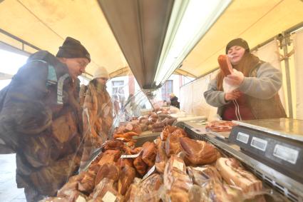 Москва.  Покупатель у мясной лавки  на ярмарке выходного дня. Ярмарки выходного дня возобновили свою работу в городе.