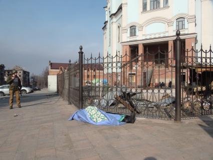 Украина. г.Мариуполь. У входа в храм лежит труп старушки, накрытый скатертью. Женщина ждала гуманитарку, а потом легла на асфальт и умерла.