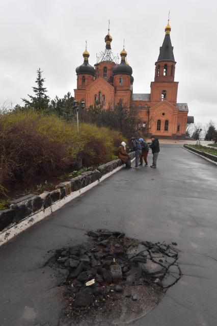 Украина. г.Мариуполь. Левобережный район. На смотровой площадке храм Архистратига Михаила, обстрелянный армией ВСУ. Воронка от бомбы на дороге к храму.