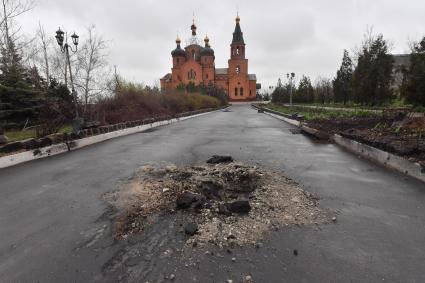 Украина. г.Мариуполь. Левобережный район. На смотровой площадке храм Архистратига Михаила, обстрелянный армией ВСУ. Воронка от бомбы на дороге к храму.