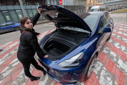 Москва. Девушка у электрокара Tesla Model Y оператора каршеринга `Ситидрайв`.