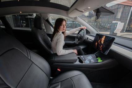 Москва. Девушка в электрокаре Tesla Model Y оператора каршеринга `Ситидрайв`.