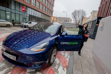 Москва. Девушка у электрокара Tesla Model Y оператора каршеринга `Ситидрайв`.