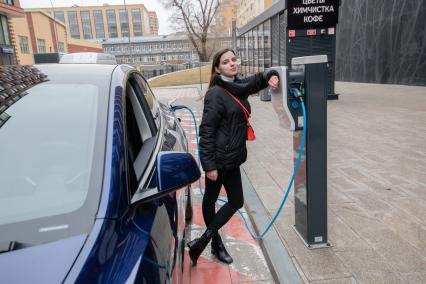 Москва. Девушка во время зарядки электрокара Tesla Model Y оператора каршеринга `Ситидрайв`.