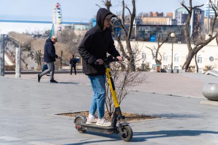 Владивосток. Молодой человек катается на электросамокате.