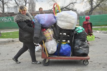 Украина. г.Мариуполь. Женщина везет на тележке вещи.