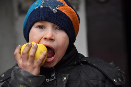 Украина. г.Мариуполь. Раздача гуманитарной помощи местным жителям. Мальчик ест яблоко.