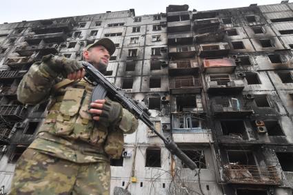 Украина. г.Мариуполь. Военнослужащий рядом с жилым домом, разрушенным в результате обстрелов.