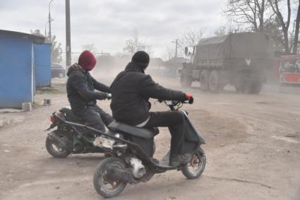 Украина. г.Мариуполь. Местные жители на мопедах смотрят на проезжающий армейский грузовик.