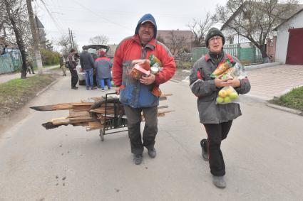 Украина. г.Мариуполь. Местные жители несут продукты и деревянные доски.