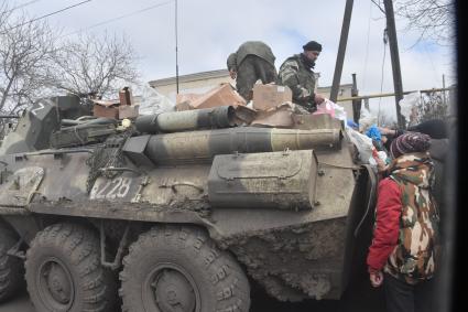 Украина. г.Мариуполь. Военнослужащие на бронетехнике раздают гуманитарную помощь местным жителям.