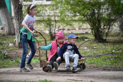 Донецкая область. г.Мариуполь. Дети катаются на тележке на одной из улиц города.