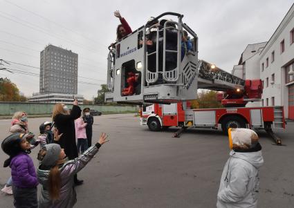 Москва. Дети в люльке пожарной машины во время посещения Московской пожарной части №31 юными спасателями и их родителями в преддверии Дня гражданской обороны и МЧС России.