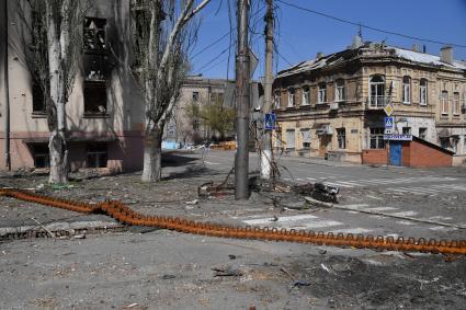 Мариуполь, Донецкая народная республика. Разрушенные, в результате обстрела, дома на улице города. противотанковая лента на дороге.