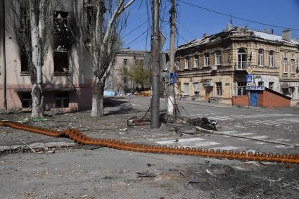 Мариуполь, Донецкая народная республика. Разрушенные, в результате обстрела, дома на  улице города. противотанковая лента на дороге.