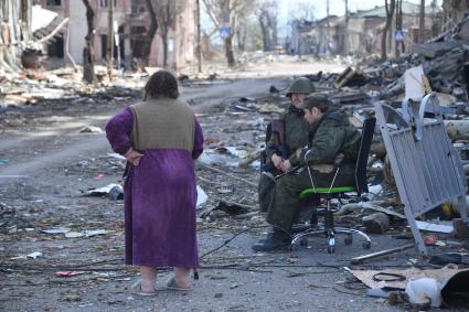 Мариуполь, Донецкая народная республика. Военнослужащие ДНР и местная жительница на улице разрушенного города.