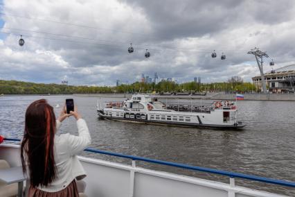 Москва. Девушка фотографирует прогулочный теплоход на Москва-реке.