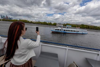 Москва. Девушка фотографирует прогулочный теплоход на Москва-реке.