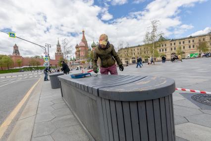 Москва. Женщина красит скамейку.