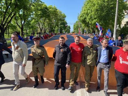 Донецкая область. г.Мариуполь. Глава ДНР Денис Пушилин (третий слева), руководитель администрации Мариуполя Константин Иващенко (третий справа), волонтеры российских общественных движений и горожане несут 300-метровую георгиевскую ленту во время шествия, в честь празднования 77-й годовщины Победы в Великой Отечественной войне.