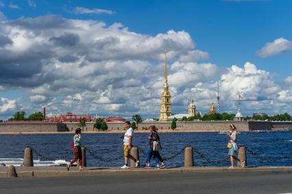 Санкт-Петербург. Люди гуляют на набережной с видом на Петропавловскую крепость.