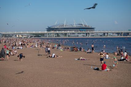 Санкт-Петербург. Люди загорают на пляже Финского залива с видом на стадион `Газпром-Арена`.