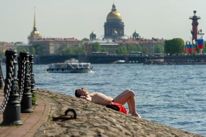 Санкт-Петербург. Мужчина загорает на набережной Невы.