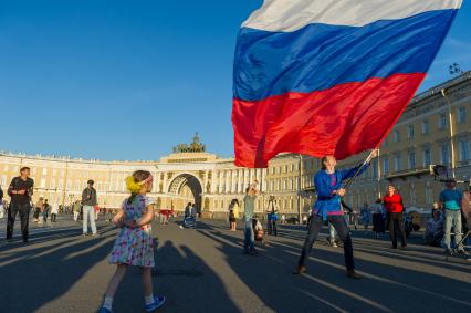 Санкт-Петербург. Люди гуляют на Дворцовой площади в рамках фестиваля `Хороводы России`. Мужчина с флагом России.