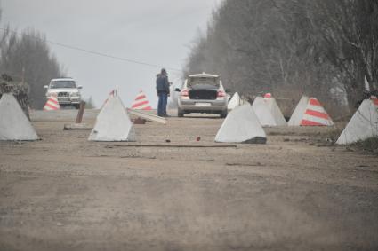 Донецкая область. г.Мариуполь. Противотанковые надолбы у КПП. Военнослужащий проверяет документы и машину у водителя.