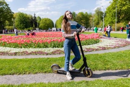 Москва. Девушка на самокате в парке.